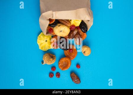 Draufsicht auf verschiedene getrocknete Früchte in einer Papiertüte Auf dem blauen Hintergrund Stockfoto