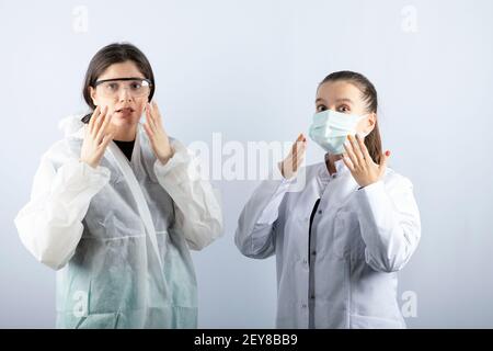 Zwei Ärztinnen in defensivem Mantel stehen überraschend Stockfoto