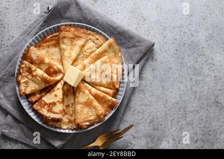 Russische dünne Pfannkuchen oder Blini mit Butter auf grauem Steintisch. Draufsicht. Fasching. Leerzeichen für Text. Stockfoto