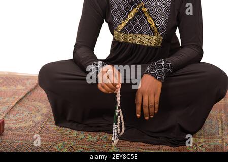Junge muslimische Frau sitzt in langen Kleid auf Matte beten. Stockfoto