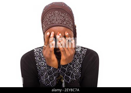 Junge muslimische isolierte Frau sitzt auf weißem Hintergrund beten. Stockfoto