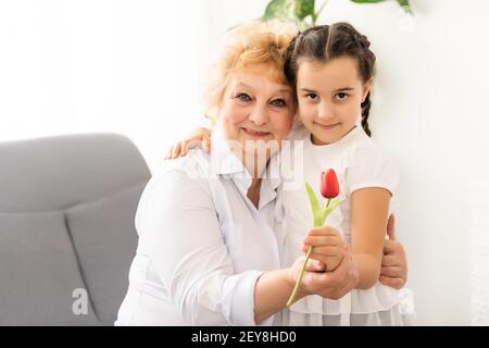 Glückliche Großmutter mit Enkelin. Frau und Kind mit Blume zu Hause Stockfoto
