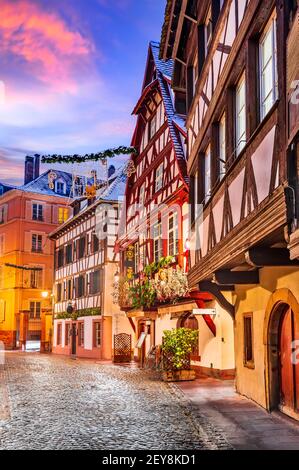 Straßburg, Frankreich. Traditionelle elsässische Fachwerkhäuser in Petite France während der Dämmerung zur Weihnachtszeit dekoriert. Stockfoto