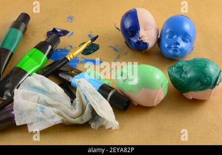 Malen Puppenköpfe mit Acryl-Tuben, Pinsel und Lappen auf Pergamentpapier Stockfoto