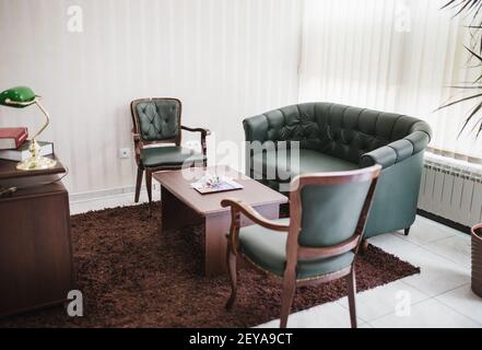 Das schöne luxuriöse und moderne grüne Ledersofa mit Stühlen Und einen Tisch im Büro Stockfoto