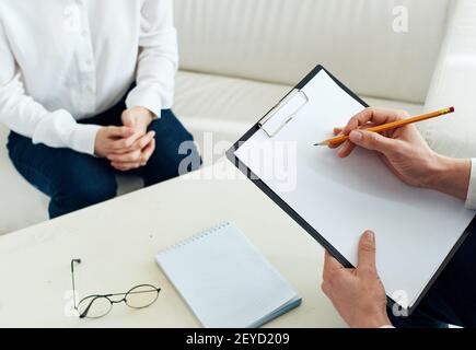 Weißes Blatt Papier ein Mann schreibt Informationen und ein Frau an einem Tisch drinnen Stockfoto