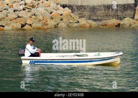 Mann beim Angeln von einem kleinen Boot in Tung Chung, Lantau Island, Hong Kong Stockfoto