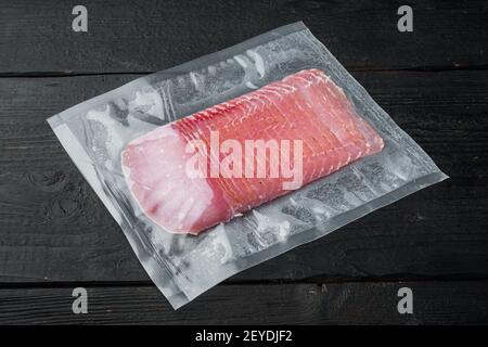 Balyk, Schweinehauch-Schinken-Set, vakuumverpackt, auf schwarzem Holztisch-Hintergrund Stockfoto