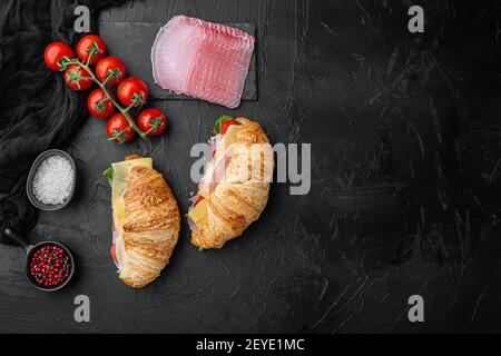 Frisches Croissant oder Sandwich mit Salat, Schinken, Jamon, Prosciutto Set, mit Kräutern und Zutaten, auf schwarzem Stein Hintergrund, Draufsicht flach Lay, mit Cop Stockfoto