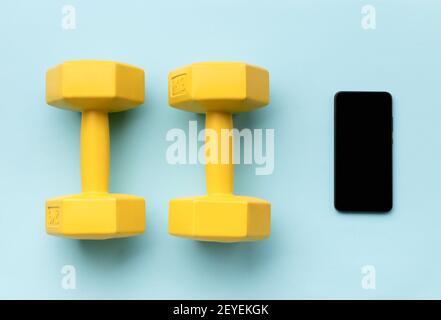 Flat Lay Top View Smartphone mit Sportgeräten auf blauem Hintergrund. Gesunde Lebensweise Online-Fitness-Konzept Stockfoto