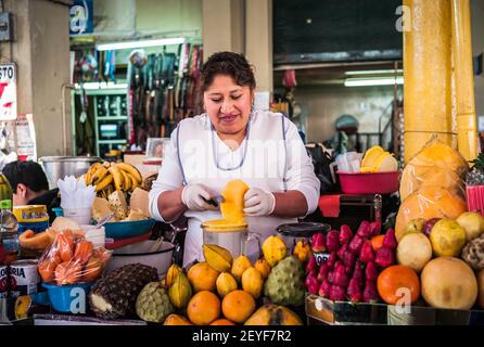 Arequipa, Peru - Juli 20 2010: Frau in der weißen Schürze entsaften Früchte an einem Marktstand im Coloful Markt Mercado San Camilo. Stockfoto