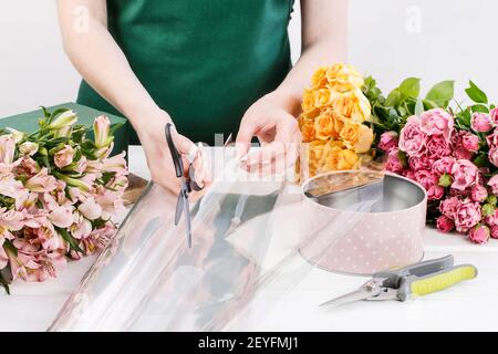 Floristin bei der Arbeit: Frau zeigt, wie man Blumenarrangement mit Rosen und anderen Blumen in einer rosa gepunkteten Dose zu machen. Schritt für Schritt, Tutorial. Stockfoto