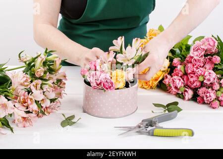 Floristin bei der Arbeit: Frau zeigt, wie man Blumenarrangement mit Rosen und anderen Blumen in einer rosa gepunkteten Dose zu machen. Schritt für Schritt, Tutorial. Stockfoto