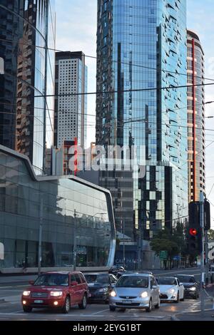 Die Autos hielten an der roten Ampel an der Kreuzung mit hohen Gebäuden mit Glaswänden im Hintergrund. Stockfoto