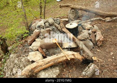 Kochen auf dem Feuer, Topf über dem Feuer, Holzlöffel auf den Steinen, Touristenessen Stockfoto