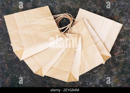 Draufsicht auf fünf braune Einkaufstaschen mit Griffen auf einem grungigen Tisch. Stockfoto