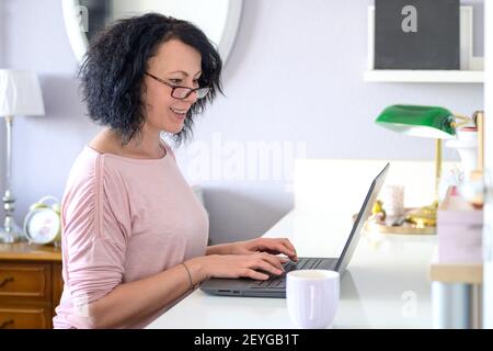 Frau arbeitet an ihrem Computer und lächelt an der Computer Stockfoto