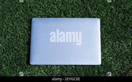 Laptop auf grünem Gras. Agiles Geschäft. Fernlernkonzept. Immer online verfügbar. Arbeiten im Frischluftpark. Computer auf Rasen. Modernes Notebook-Gerät. Digitale Umgebung. Freiberuflich. Stockfoto