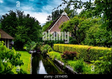 Giethoorn, Niederlande - 6. Juli 2019: Idyllische Szene mit Blumen, Bäumen, Kanälen und traditionellen ländlichen niederländischen Haus im Dorf Giethoorn, bekannt Stockfoto