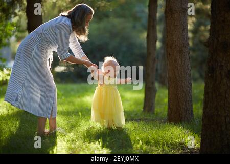 Mutter und Tochter wandern an einem Sommertag im sonnigen Park. Speicherplatz kopieren. Stockfoto