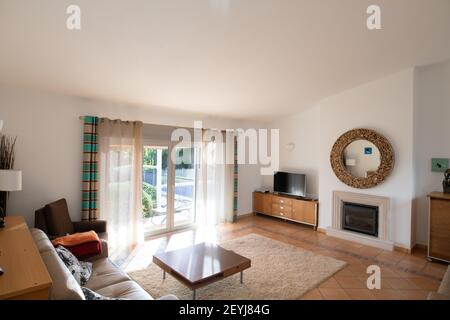 Wohnzimmer mit Fliesenboden, Terrassentüren und hoher Dachschräge Stockfoto