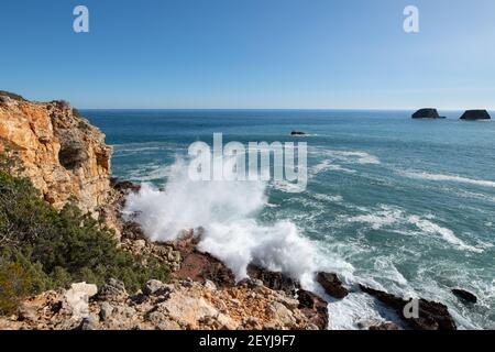 Wellen, die auf Felsen an der Küste der Algarve krachen Stockfoto
