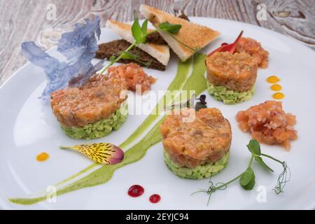 Lachs-Tartar mit Avocado auf weißem Teller Stockfoto
