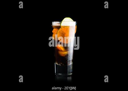 Cuba libre Cocktail auf dem rustikalen Hintergrund isoliert auf schwarzem Hintergrund. Selektiver Fokus. Stockfoto