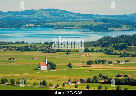 Luftaufnahme der bayrischen römisch-katholischen Barockkirche St. Coloman aus dem 17. Jahrhundert und des Forggensees im Hintergrund, Schwangau, Bayern Stockfoto