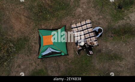 Luftaufnahme der Familie auf dem Campingplatz von oben, Eltern und Kind entspannen und liegen auf karierten, Familiencampingkonzept Stockfoto