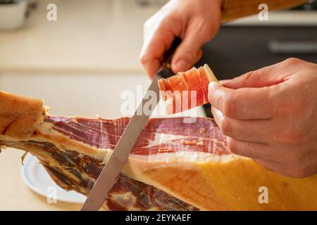 Detail von Schinken laufen von Menschenhand in der Küche zu Hause gemacht. Super Essen. Köstliche Vorspeise. Gourmet-Food-Konzept Stockfoto