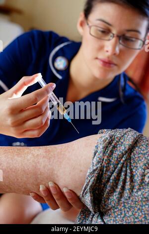 Krankenschwester, die einer älteren Frau einen Grippeanstrich gibt Stockfoto