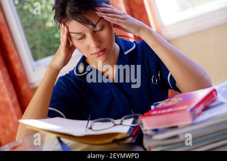 Krankenschwester müde, als sie für Prüfungen überarbeitet Stockfoto