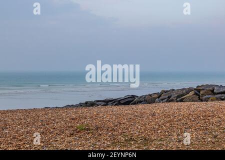 Blick auf das Meer über Kiesel und Felsen, am Shoreham Beach in West Sussex Stockfoto