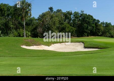 Detail eines Golfplatzes mit Sandfallen, Bunker in Mexiko. Im Hintergrund sind die Vegetation und die Bäume des tropischen Gebietes. Stockfoto