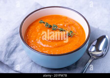 Kürbiscremesuppe mit Thymian in einer Schüssel. Vegetarische hausgemachte Suppe. Grauer Hintergrund, Nahaufnahme. Stockfoto