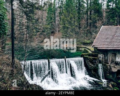 Eine schöne Aufnahme eines alten Holzhauses daneben Ein Wasserfall in Stockfoto
