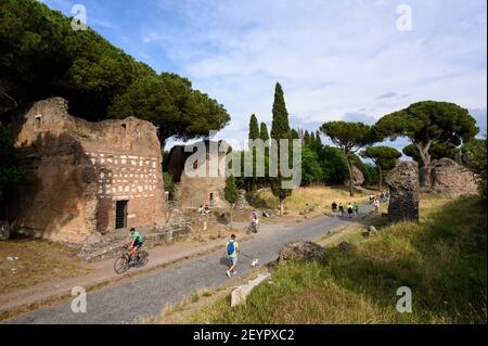 Rom Italien. Via Appia Antica (Appian Way), Menschen zu Fuß und mit dem Fahrrad zwischen alten römischen Grabdenkmälern. L-R; Primo Monumento in Lateriz Stockfoto