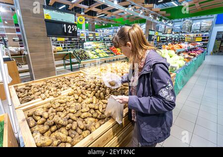 Samara, Russland - 5. September 2017: Junge Frau, die frische Kartoffeln beim Einkaufen im Hypermarkt der Kette wählt Stockfoto