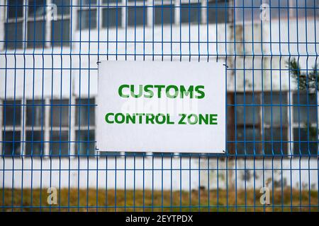 Zollkontrollzone Schild mit grünen Buchstaben auf Metallzaun, Warnung vor dem Betreten spezieller Bereich. Sicherheitskontrolle des Logistikkomplexes, Fahrzeug in Stockfoto