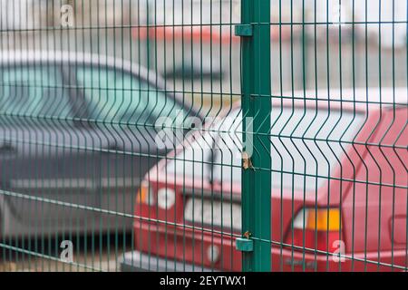 Eingezäunter Parkplatz mit Sicherheit. Bewachtes Gebiet des bezahlten stündlichen Parkens. Unscharfe Autos Hintergrund Stockfoto