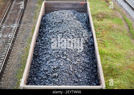 Eisenbahn-Güterwagen mit Kohle beladen. Güterzug transportiert Kohle, Holz, Brennstoff. Draufsicht. Stockfoto