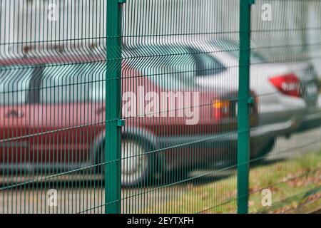 Eingezäunter Parkplatz mit Sicherheit. Bewachtes Gebiet des bezahlten stündlichen Parkens. Unscharfe Autos Hintergrund Stockfoto