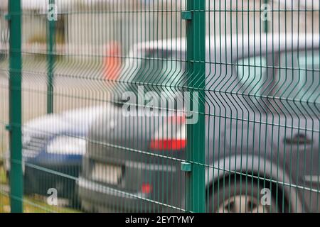 Eingezäunter Parkplatz mit Sicherheit. Bewachtes Gebiet des bezahlten stündlichen Parkens. Unscharfe Autos Hintergrund Stockfoto