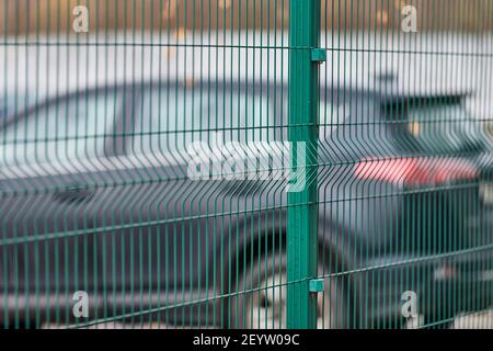 Eingezäunter Parkplatz mit Sicherheit. Bewachtes Gebiet des bezahlten stündlichen Parkens. Unscharfe Autos Hintergrund Stockfoto