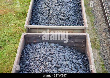 Eisenbahn-Güterwagen mit Kohle beladen. Güterzug transportiert Kohle, Holz, Brennstoff. Draufsicht. Stockfoto