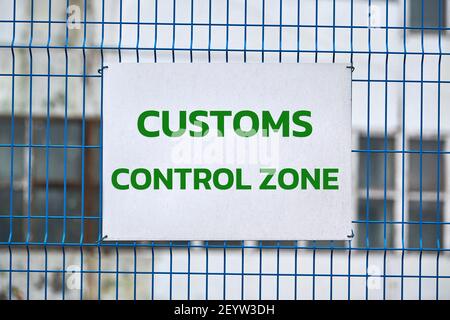 Zollkontrollzone Schild mit grünen Buchstaben auf Metallzaun, Warnung vor dem Betreten spezieller Bereich. Sicherheitskontrolle des Logistikkomplexes, Fahrzeug in Stockfoto