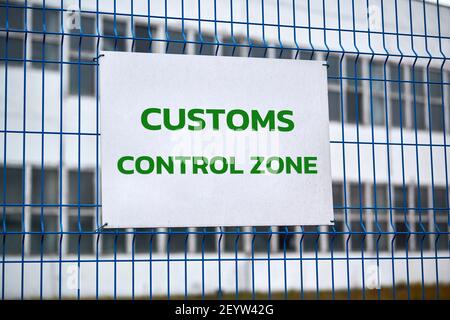 Zollkontrollzone Schild mit grünen Buchstaben auf Metallzaun, Warnung vor dem Betreten spezieller Bereich. Sicherheitskontrolle des Logistikkomplexes, Fahrzeug in Stockfoto