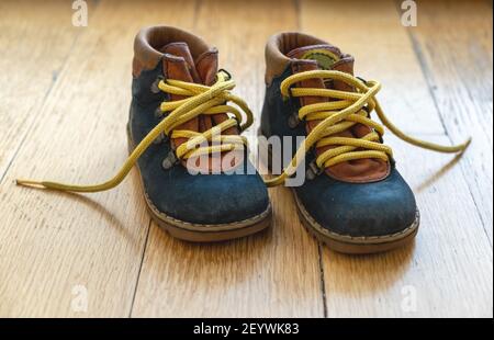 Kleine Kinderbooties Nahaufnahme. Baby Schuhe blau Farbe Leder mit gelben unbanden Schuh Schnürsenkel auf Holzboden. Stockfoto