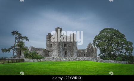 Schöne alte Ruinen der christian Bective Abbey aus dem 12th. Jahrhundert mit grünen Bäumen, Weide und launisch dunklen Himmel im Hintergrund, County Meath, Irland Stockfoto